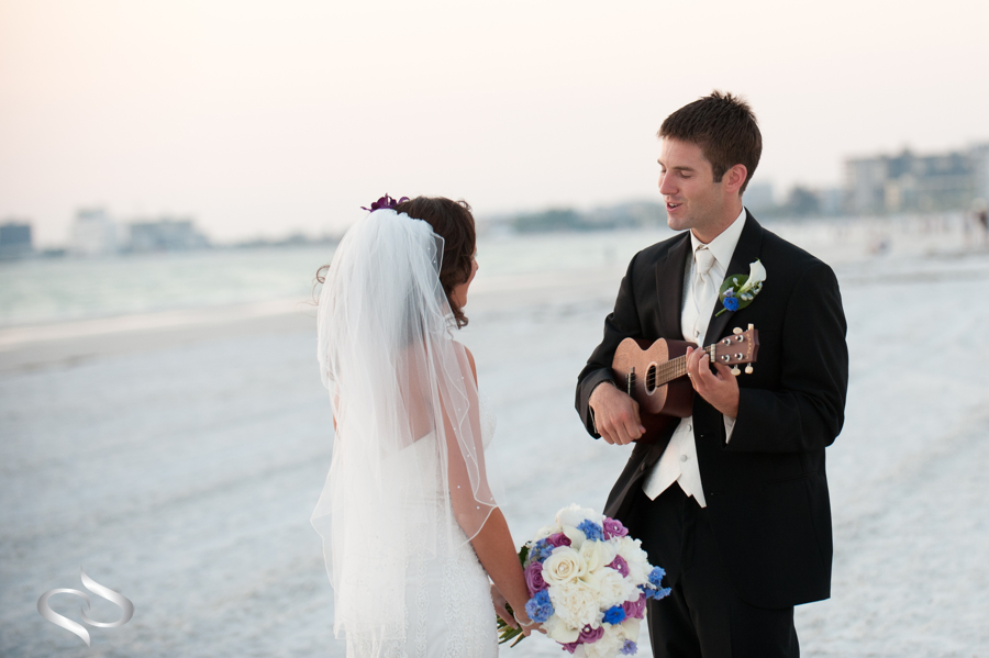 Groom serenading bride on beach