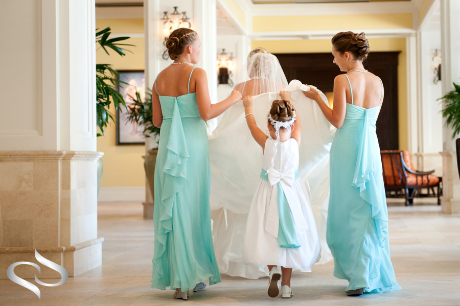 Cute Flower girl helping Bride with dress